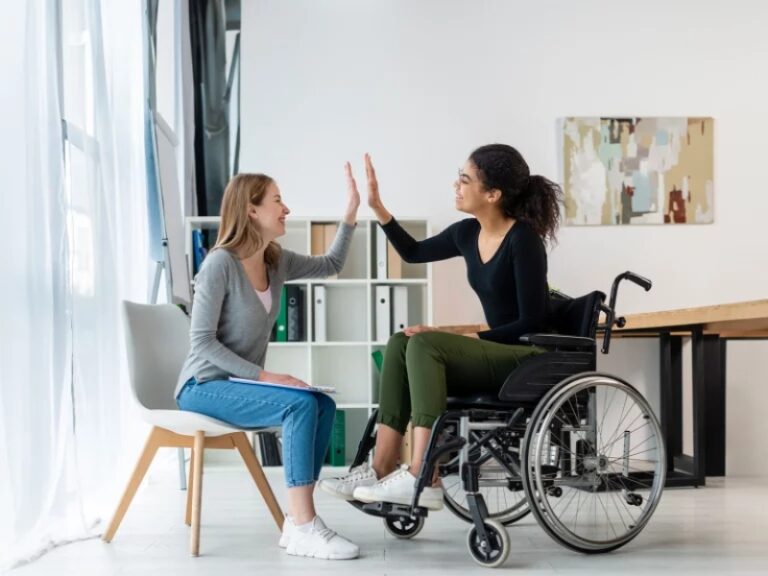 Women sharing high five during ndis home and living supports session.