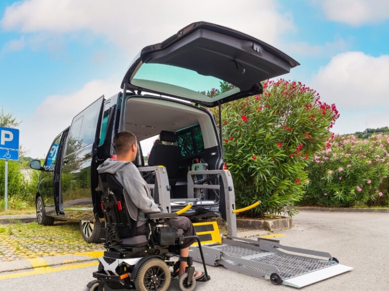 Young man in wheelchair waits at accessible van, highlighting the importance of reliable transportation services for daily mobility.
