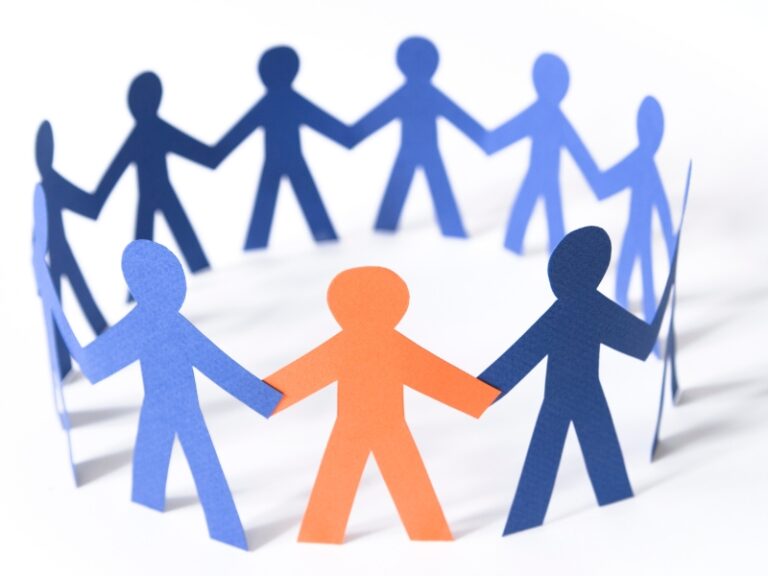Paper cutout figures holding hands symbolising unity and inclusion in social support chronic illness community.